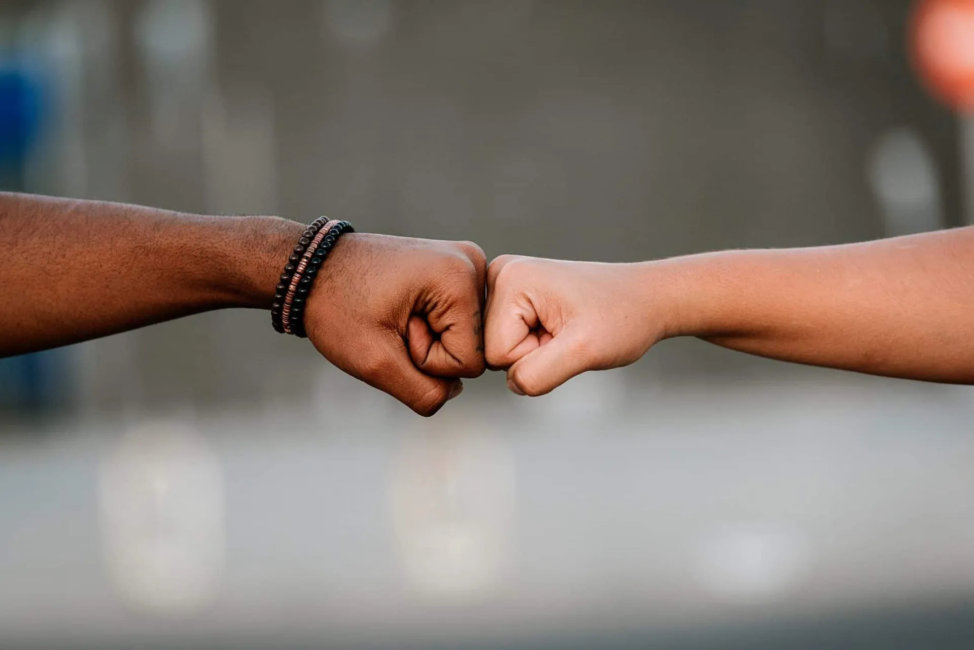 Two people of different skin tones meeting in a supportive fist bump