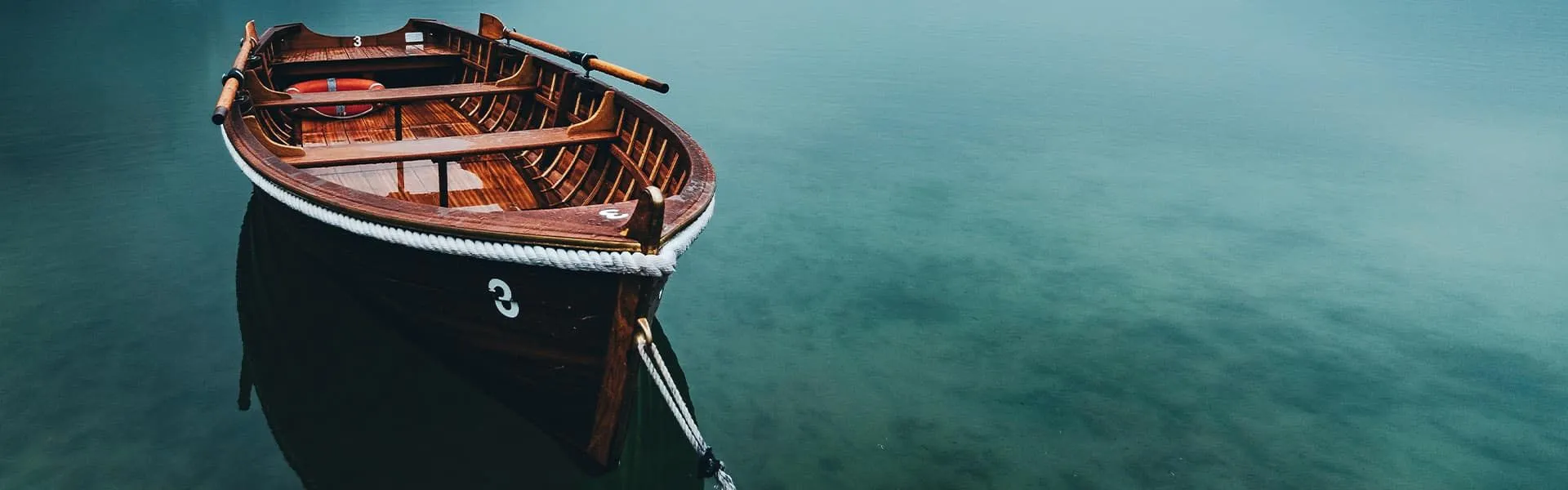 A wooden boat resting on calm teal water