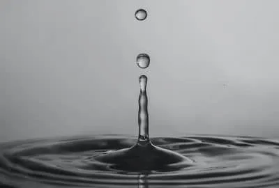 A single drop creating ripples in calm water